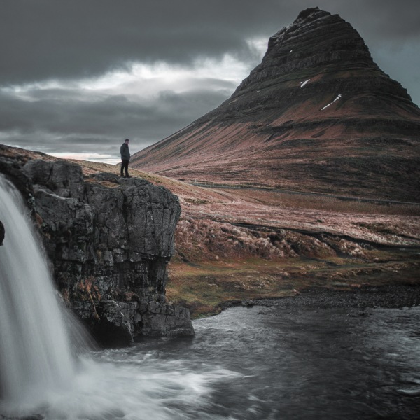 Events Guys A guy standing in front of a majestic waterfall in Iceland.