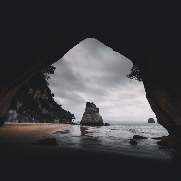 Events Guys An image of a stunning cave nestled on a picturesque beach in New Zealand.