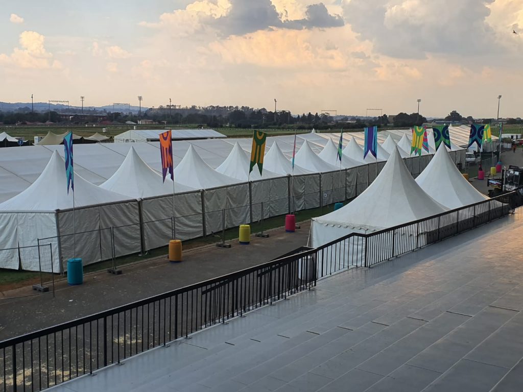 Events Guys Guys setting up white tents with flags in the background for an event.