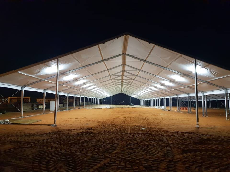 Events Guys A large tent hosting a lively event in the desert at night, filled with excited guys.