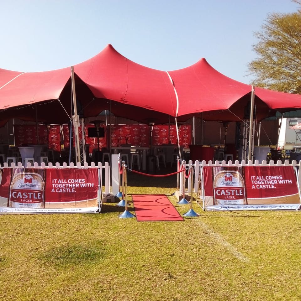 Events Guys A red tent set up in a grassy area for events.