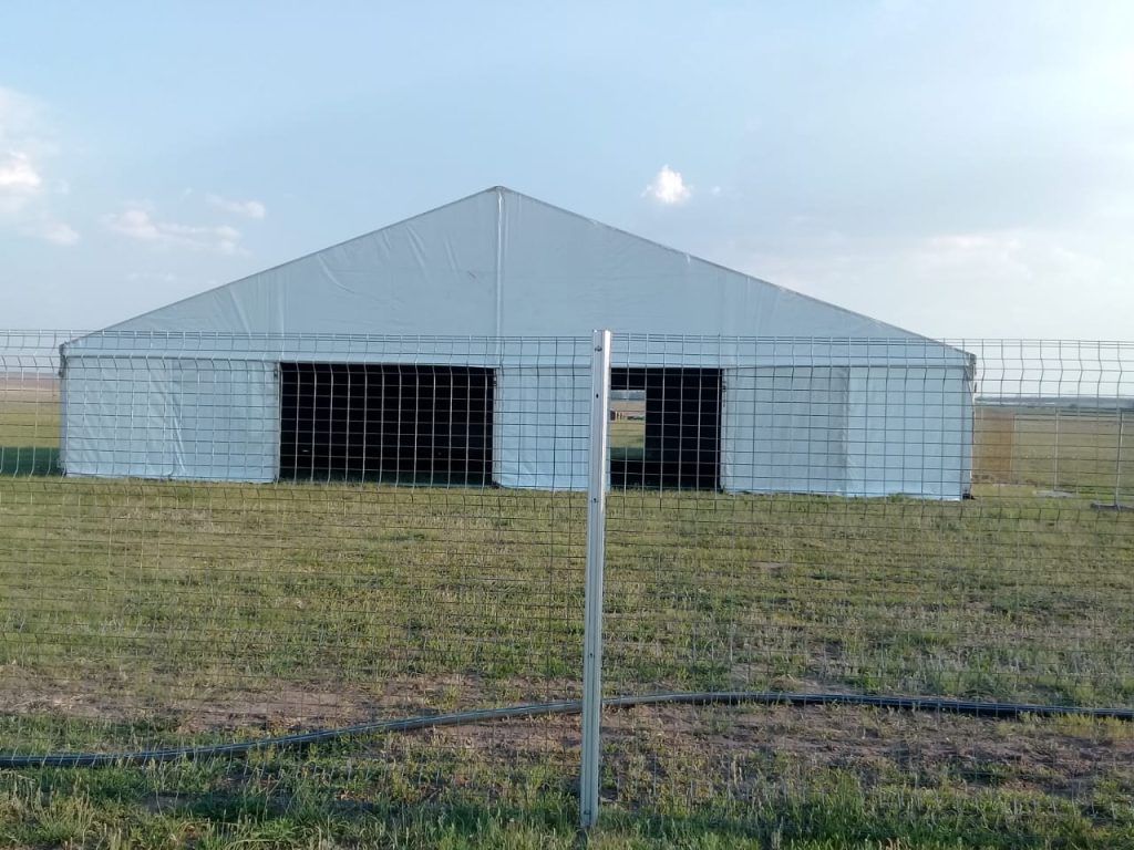 Discover South Africa's Best Waterproof Stretch Tents Today 2 Events Guys A stretchy white tent in a field next to a fence.