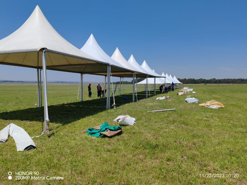 Events Guys Stretch tents on a grassy field.